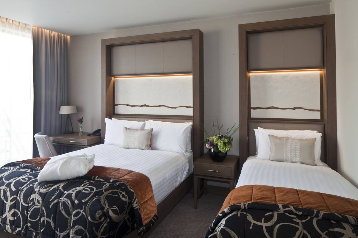 A hotel room with two beds, a desk, and a nightstand.