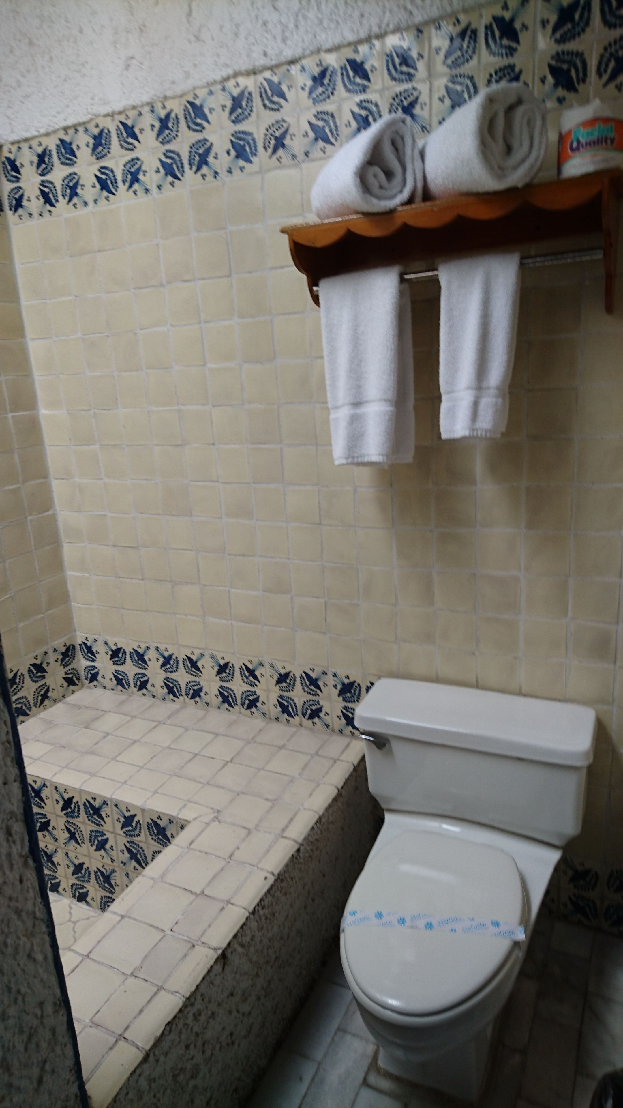 A bathroom with a bathtub, toilet, and a shelf with towels.
