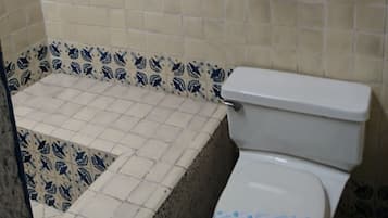 A bathroom with a bathtub, toilet, and a shelf with towels.