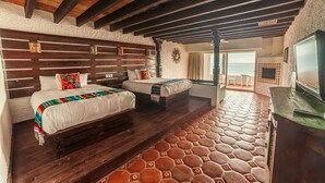 Une chambre avec deux lits, un plafond en bois et une vue sur la mer.