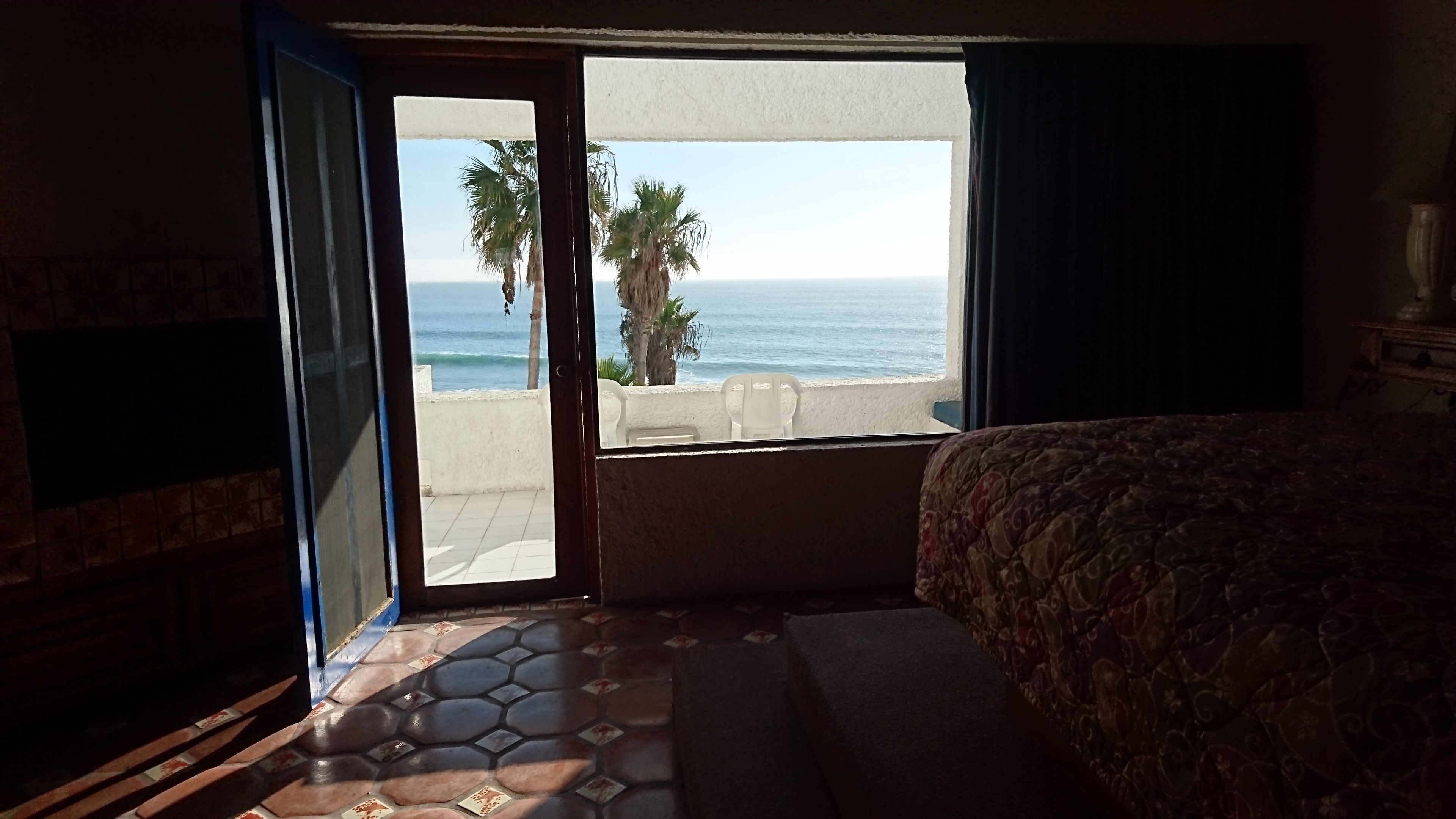 Ein Hotelzimmer mit Bett, Meerblick und Balkon mit Stühlen.