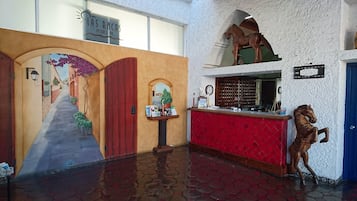Un hall d’hôtel orné d’une fresque murale, avec un comptoir d’accueil et une statue de cheval.