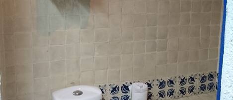 A bathroom with a toilet, a towel rack with towels, and a shelf with toiletries.