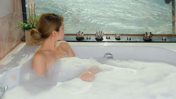Relax in a serene space with a bathtub and potted plant, offering a view of the water outside.