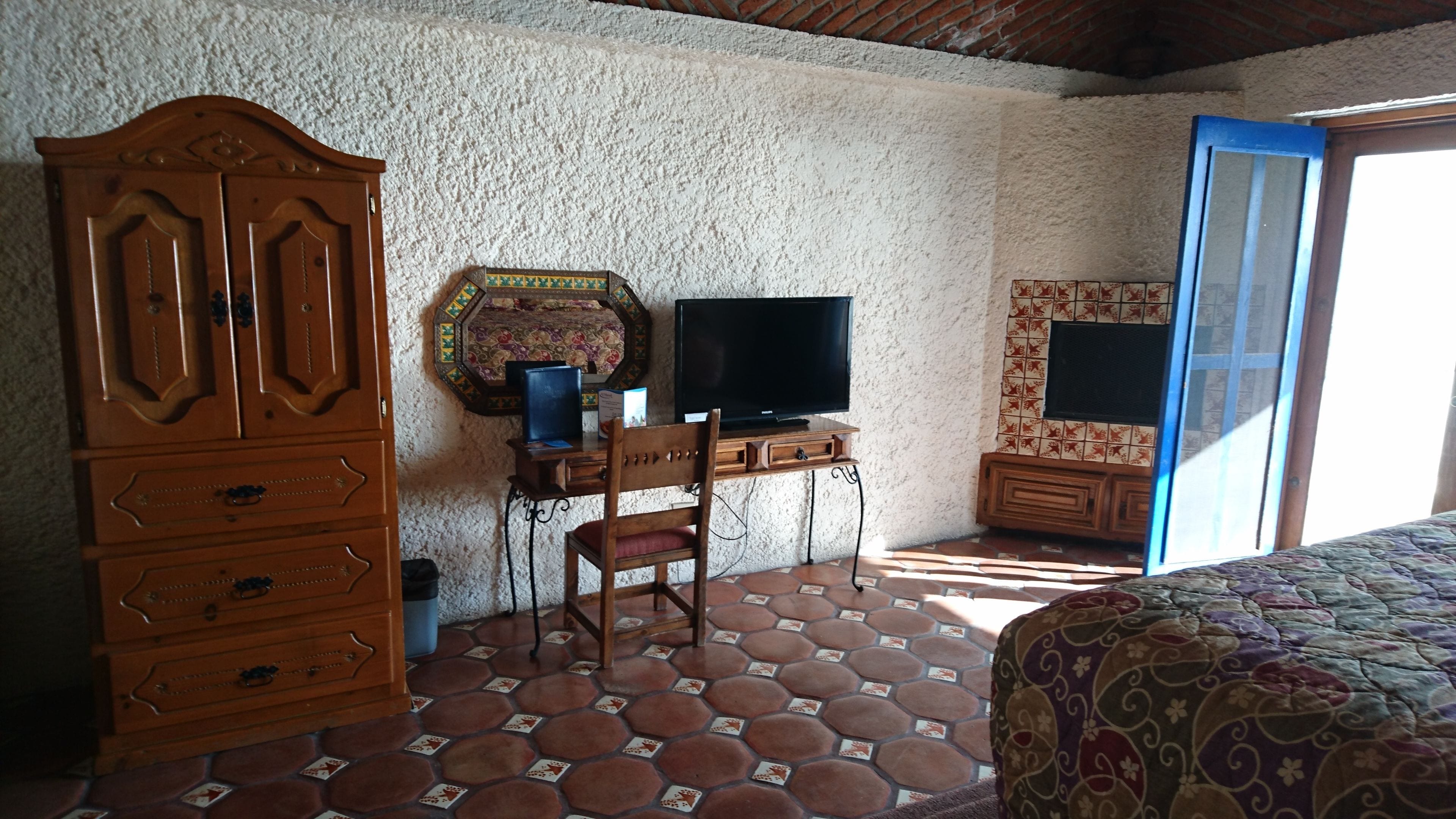 Una habitación con un armario de madera, un escritorio con televisor y una pared con diseño.