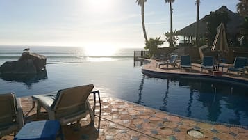 A poolside area with lounge chairs and a view of the ocean.