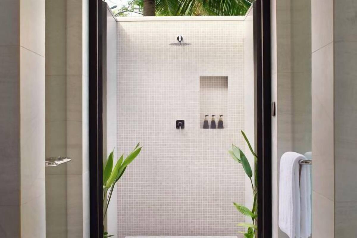 Une salle de bain moderne avec une douche carrelée, un porte-serviettes et une petite étagère contenant des articles de toilette.