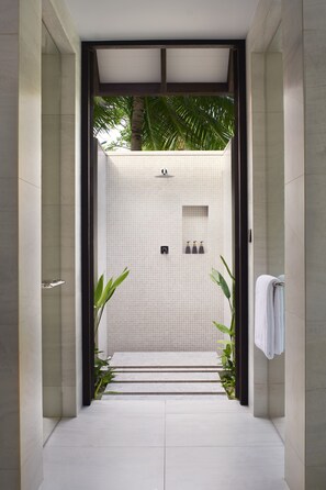 Een moderne badkamer met een betegelde douche, een handdoekrek en een potplant.