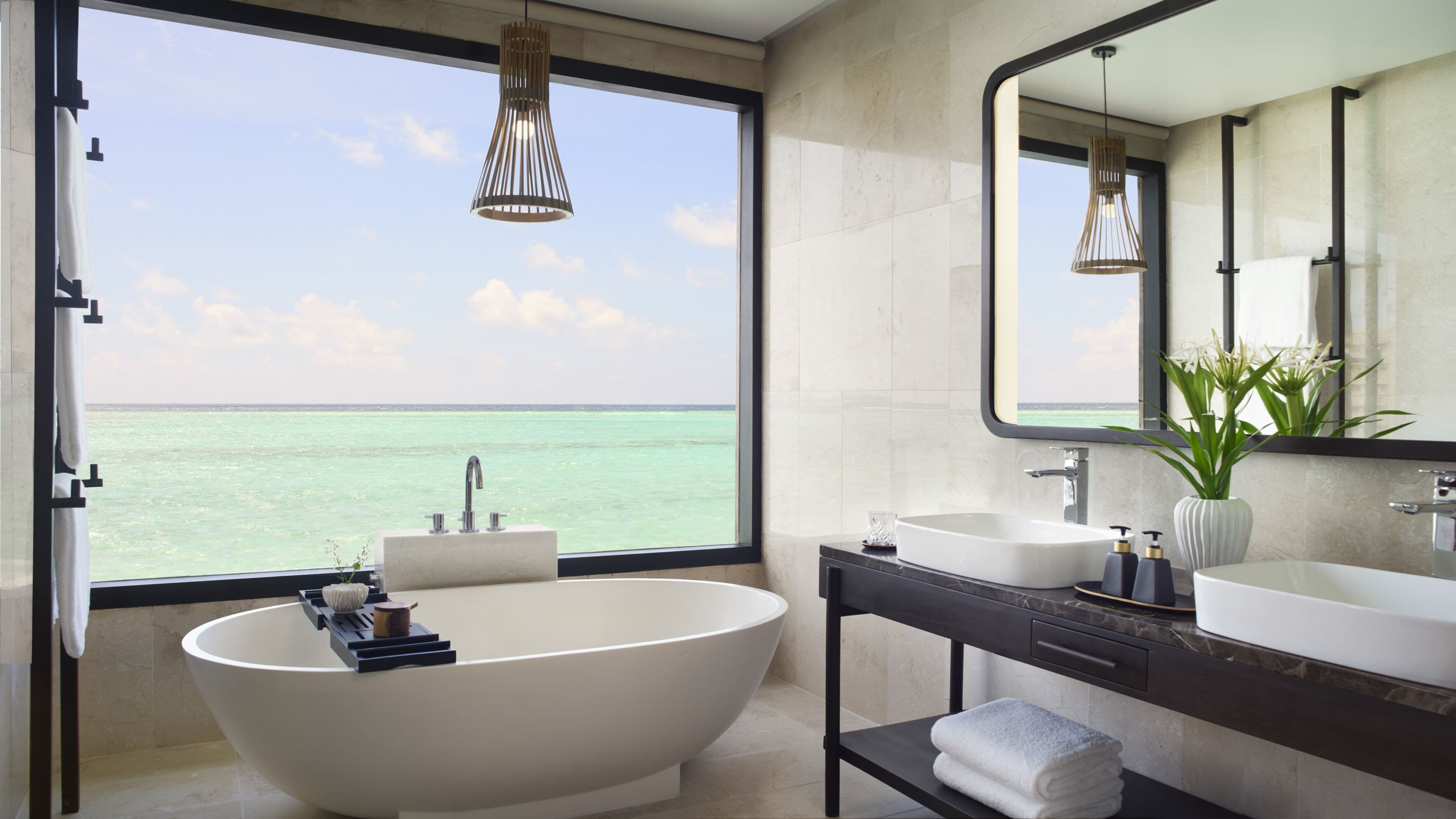 Un baño moderno con una bañera independiente, un tocador con espejo y vistas al océano.