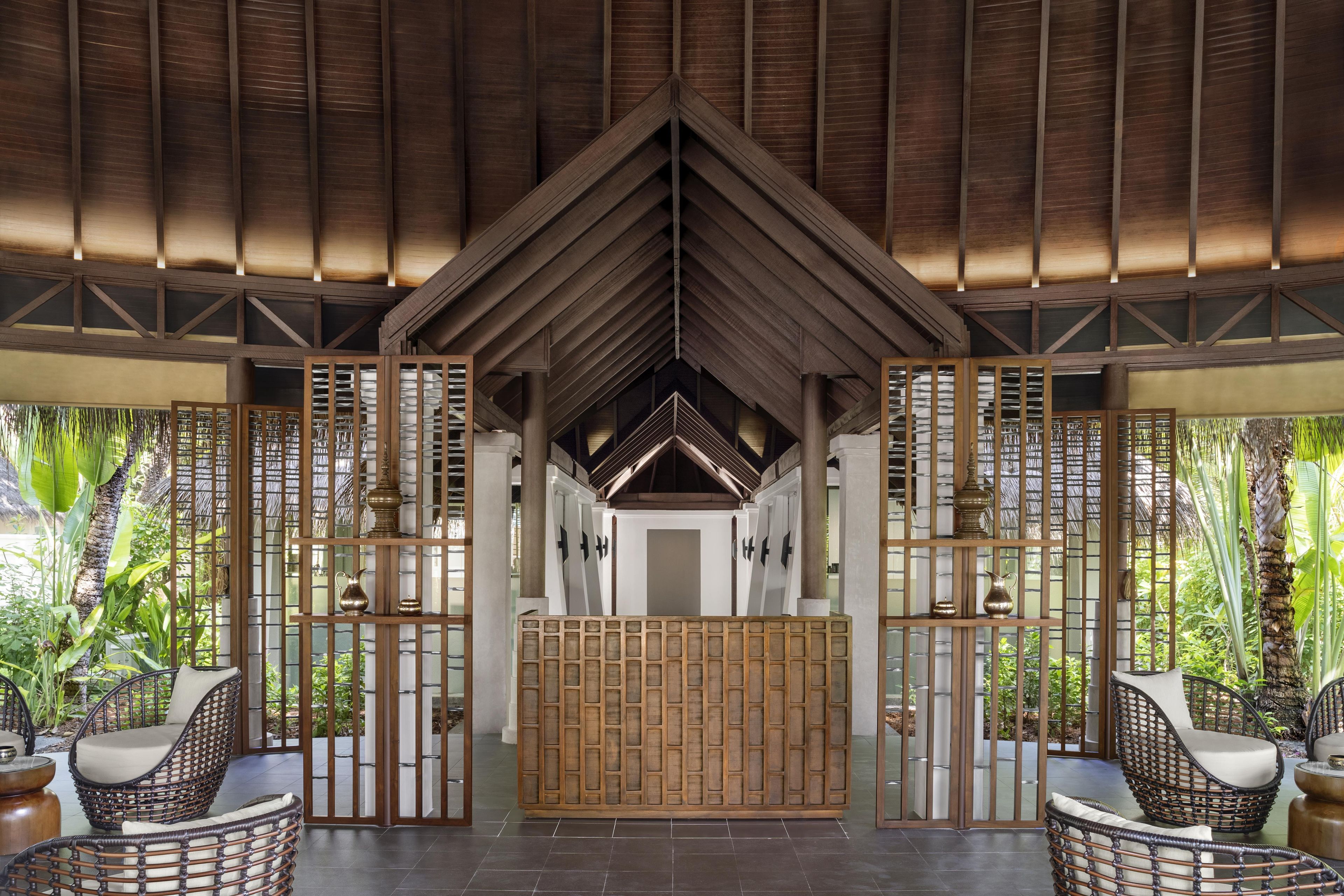 A covered outdoor seating area with wicker chairs and a bamboo partition.