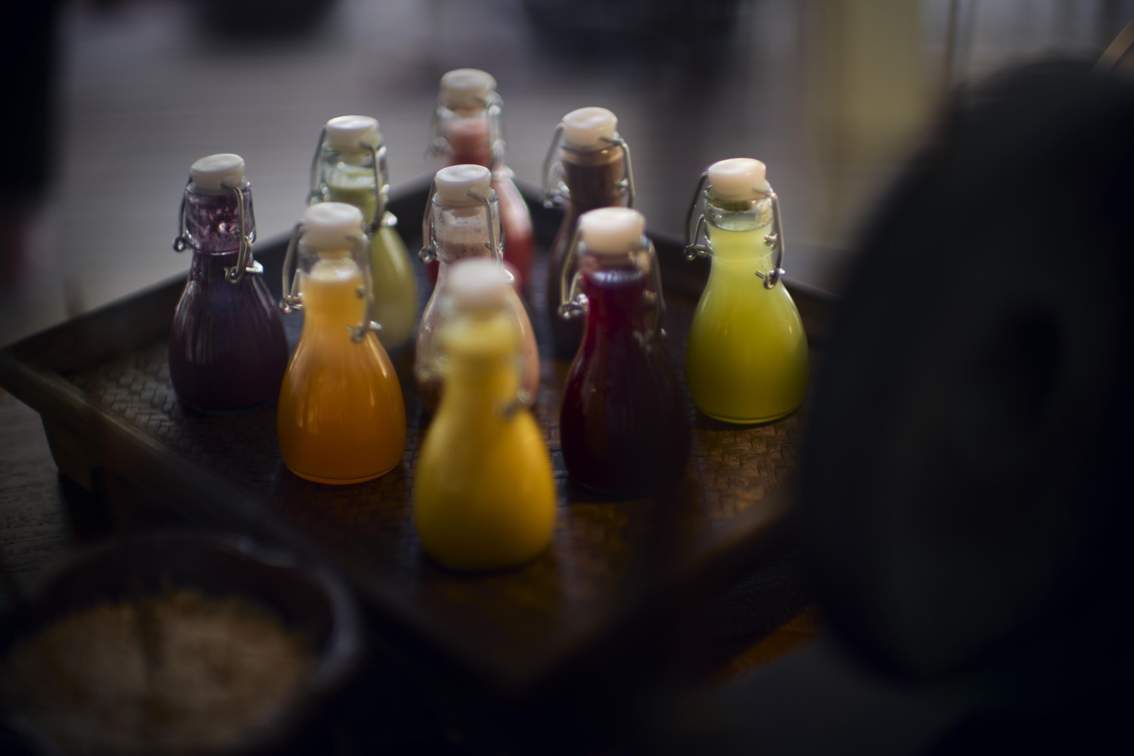 A tray with various colored liquids in glass bottles.