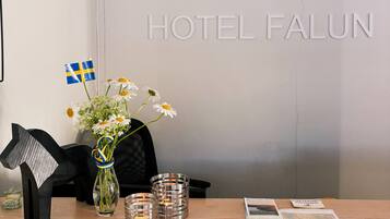 A reception desk with a vase of flowers, a Swedish flag, and a map of Falun.
