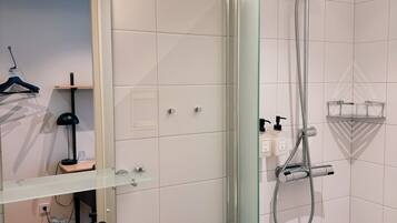 Une salle de bain moderne avec une douche à parois de verre, un lavabo blanc et un miroir au-dessus du lavabo.