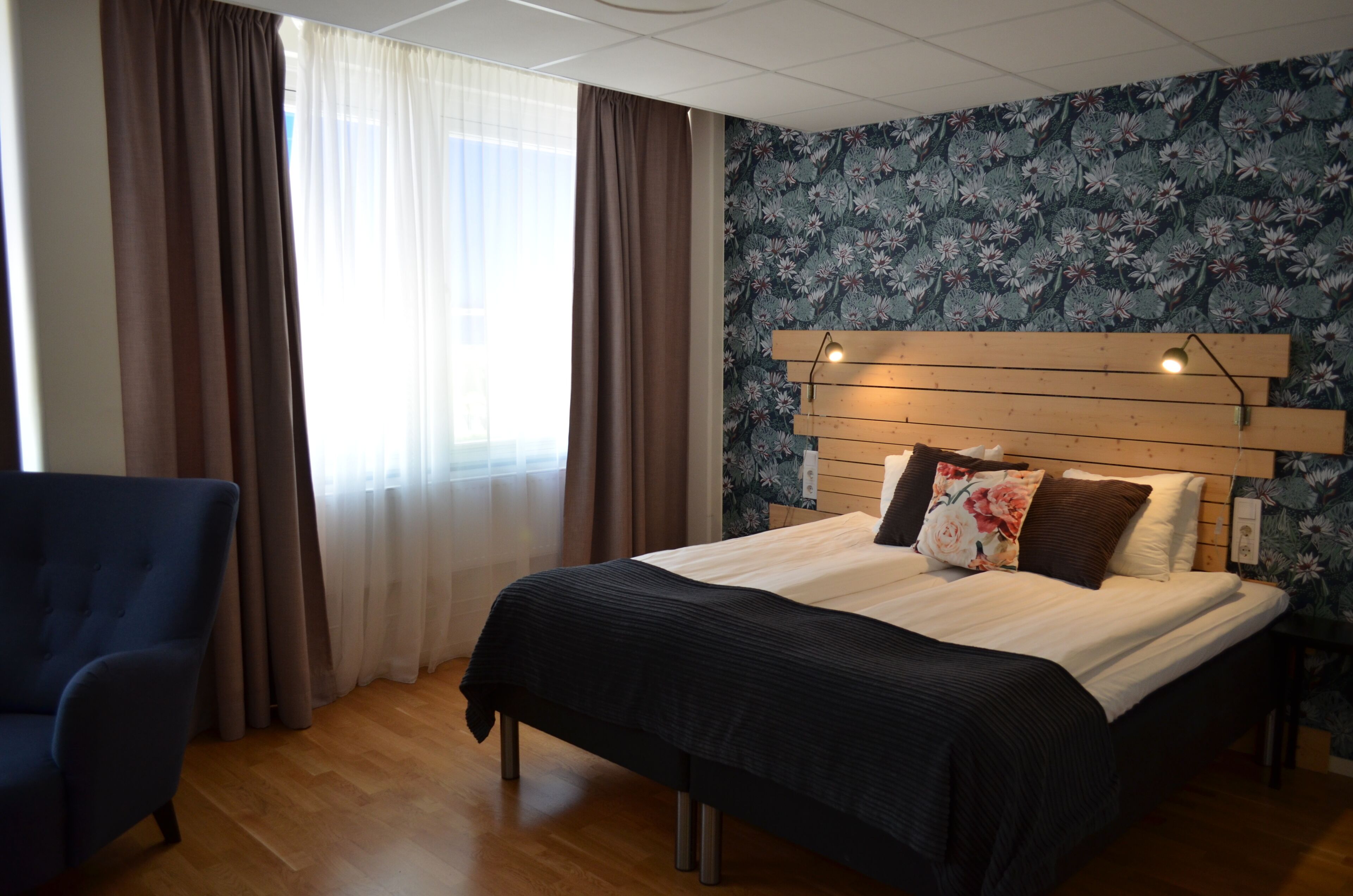 A bedroom with a bed, a chair, and a window with curtains.