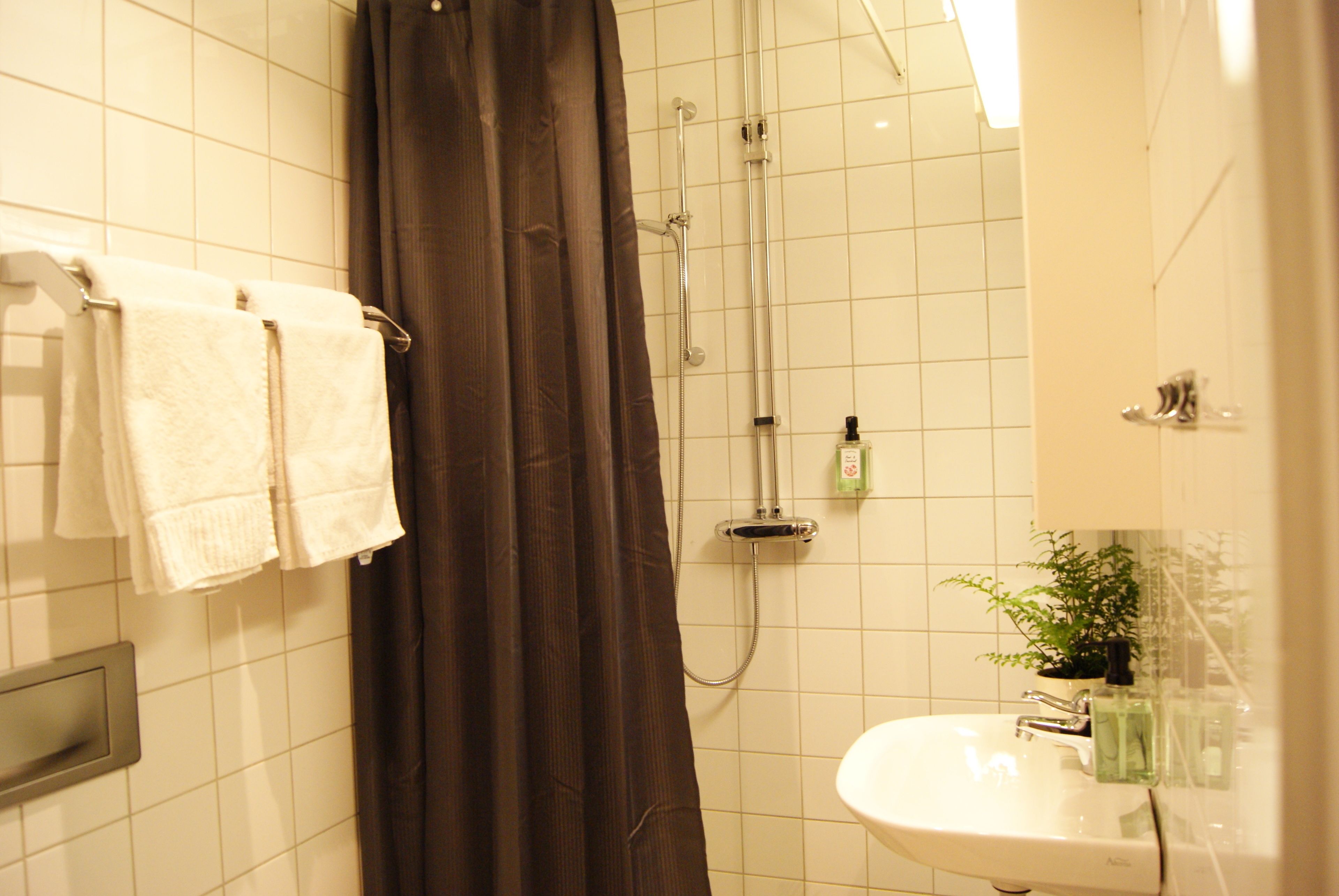 A bathroom with a shower, a sink, and a towel rack with towels.