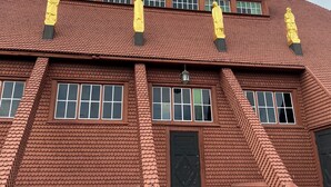 Un edificio grande con un techo empinado, muchas ventanas y una chimenea destacada.