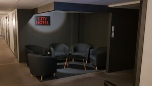 A hotel room with a dark-colored sofa set, a small table, and a sign indicating it is a City Hotel.