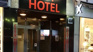The exterior of the City Hotel with a glass entrance and a sign above the door.