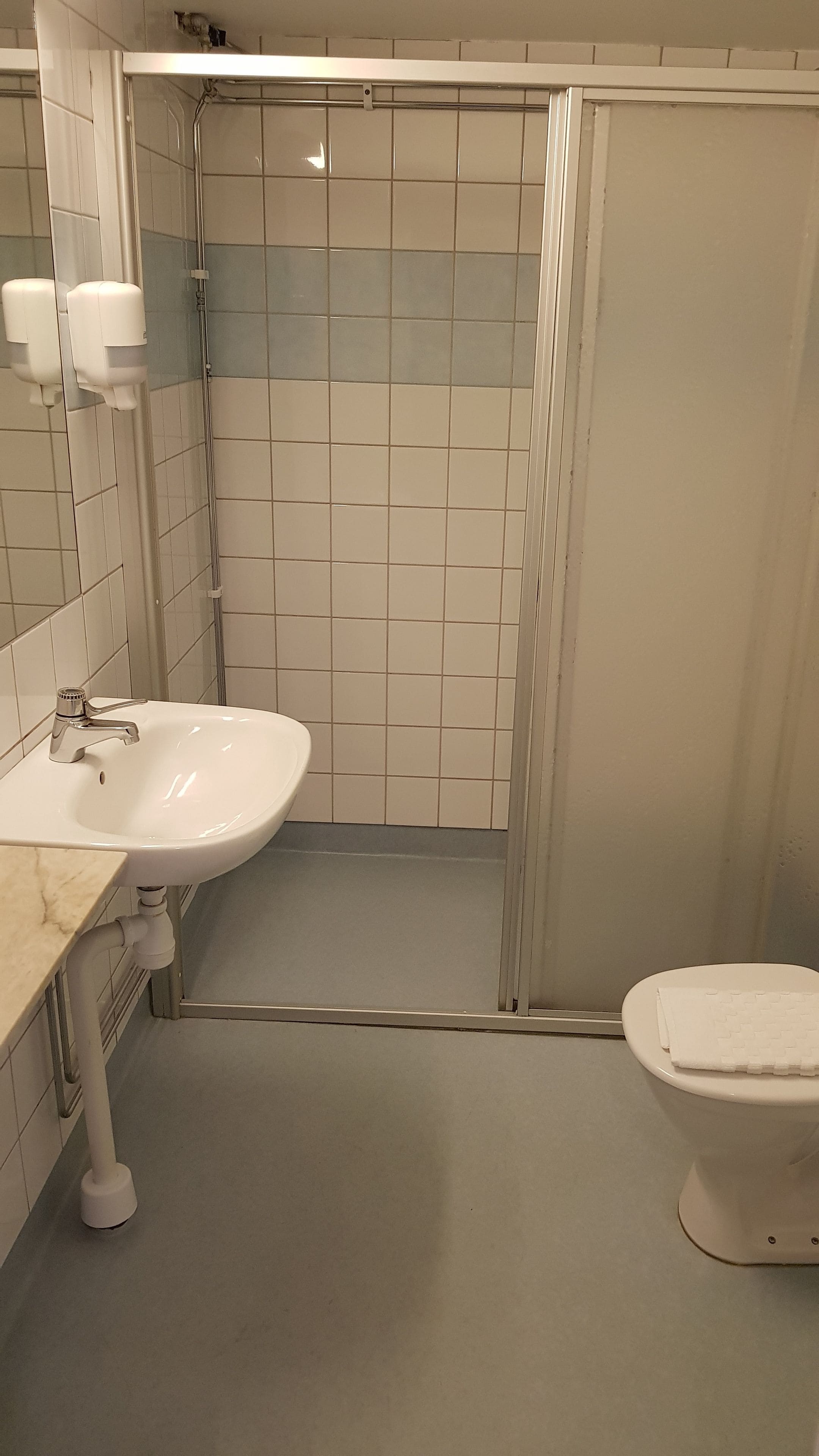 A bathroom with a white sink, a toilet, and a shower area.