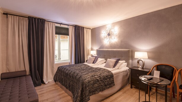 A modern bedroom with a bed, bedside tables, a desk, and a chair. - Kjøbmandsgaarden Hotel (Lindesnes)