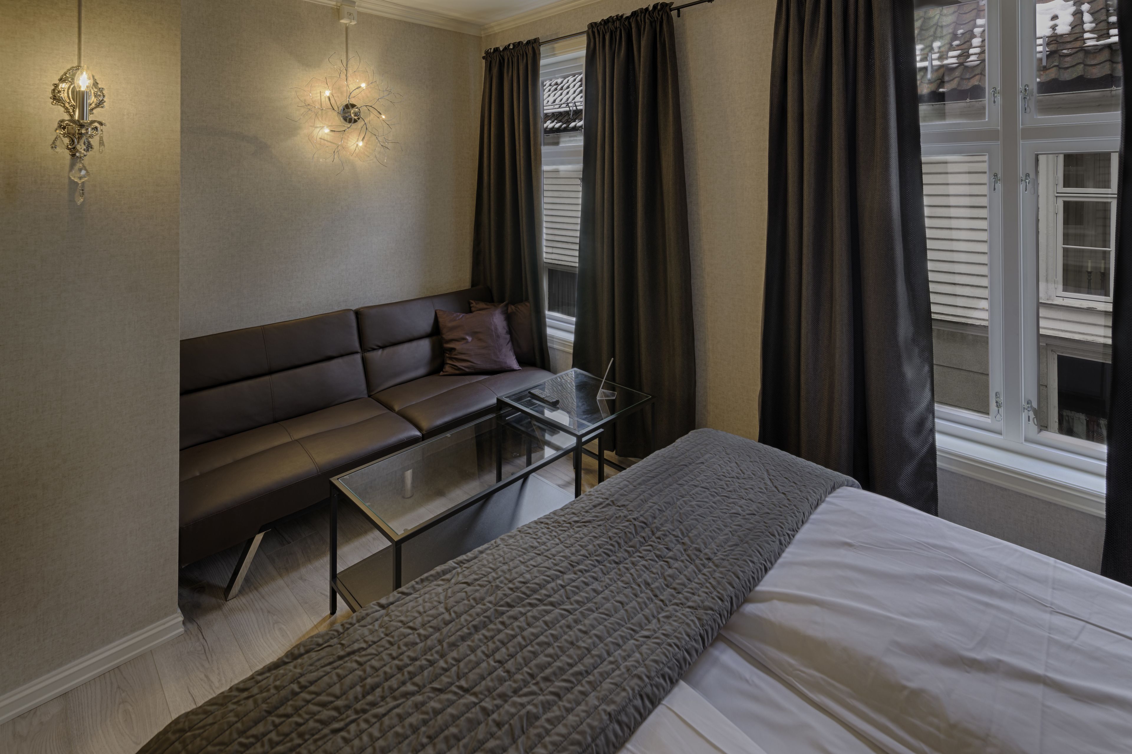Une chambre à coucher avec un lit, un canapé, une table en verre et une fenêtre avec des rideaux.
