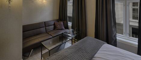 Une chambre à coucher avec un lit, un canapé, une table en verre et une fenêtre avec des rideaux.