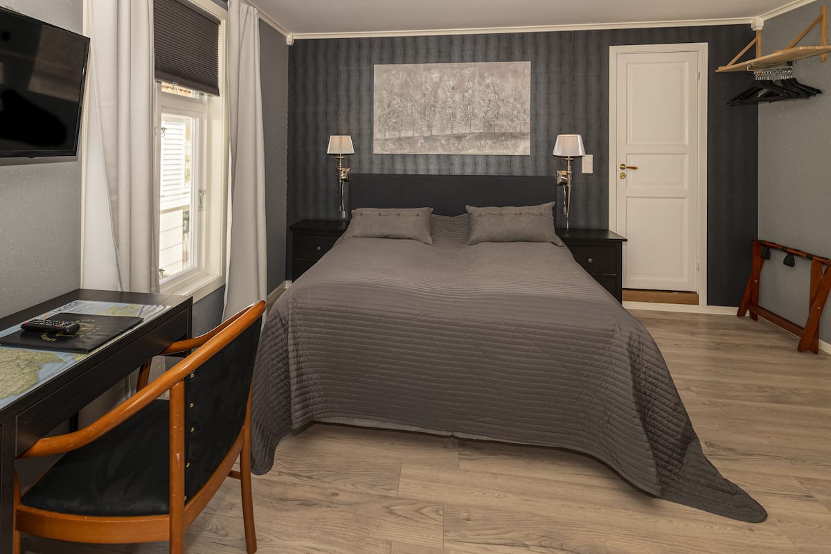 A bedroom with a bed, bedside tables, a desk, and a chair.