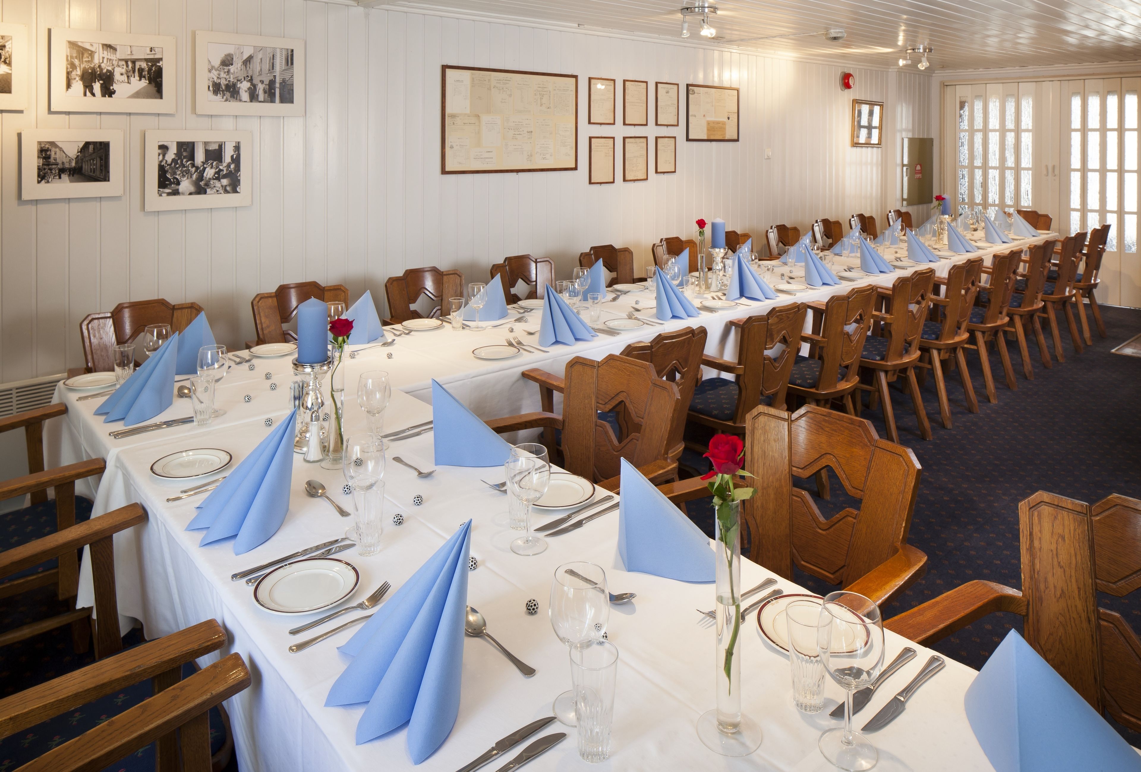 A long dining table set for a formal event with blue napkins, silverware, and glassware.