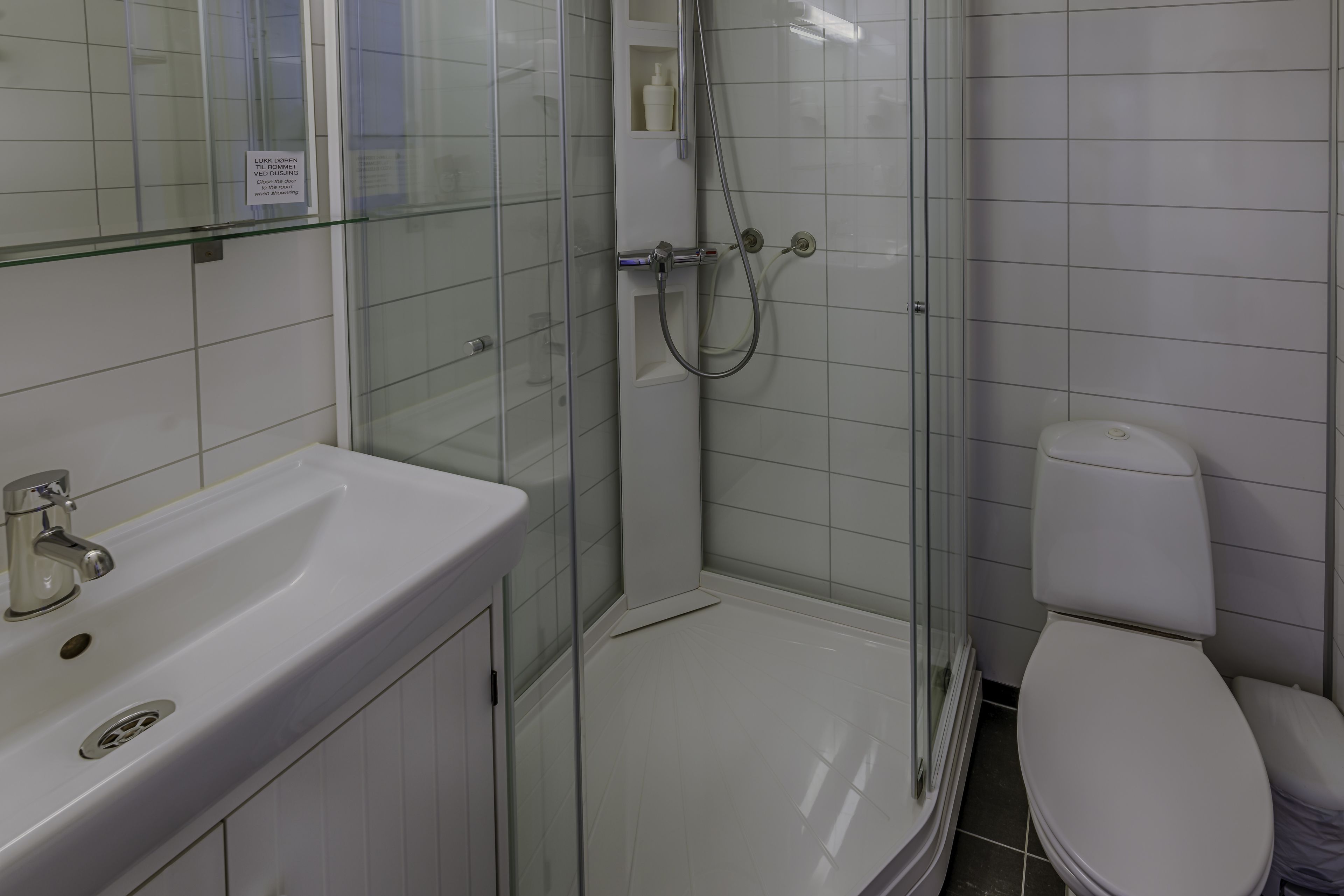 A bathroom with a glass-enclosed shower, a white sink, and a toilet.