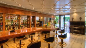 Zona de bar con mostrador de madera, varios taburetes y un piano.