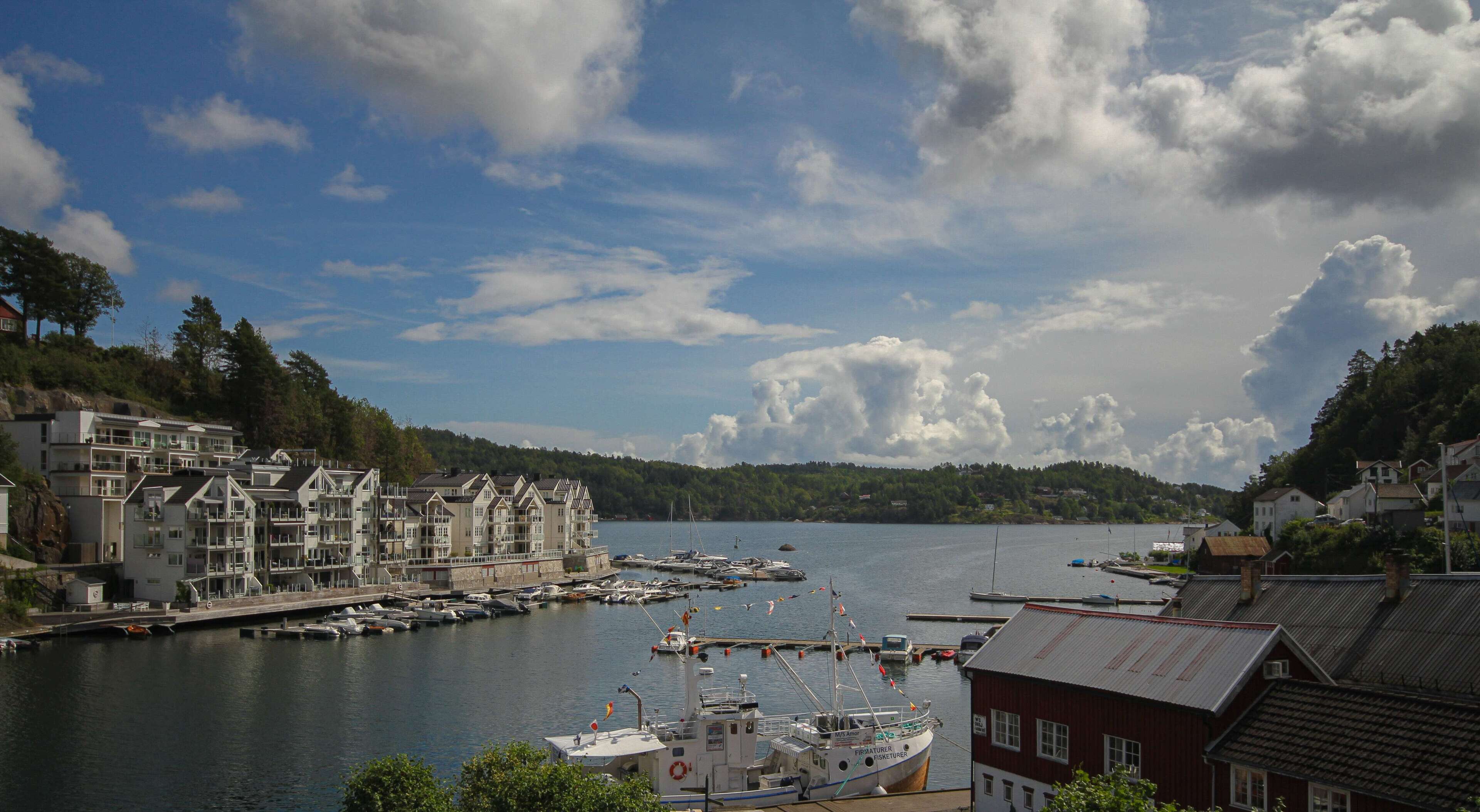 A harbor with boats docked, a marina, and buildings along the waterfront.