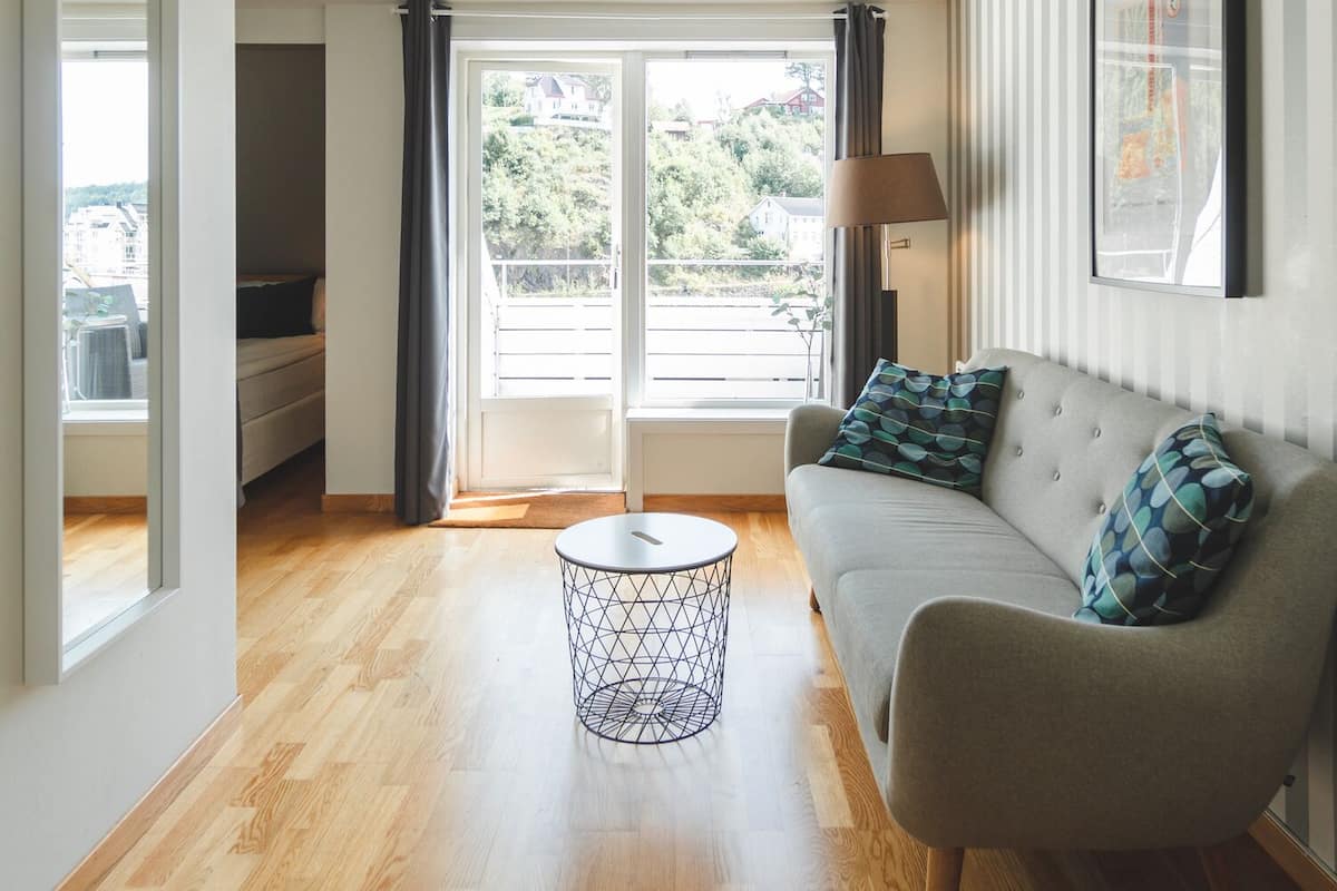 A modern living room with a sofa, a coffee table, and a view through a glass door.