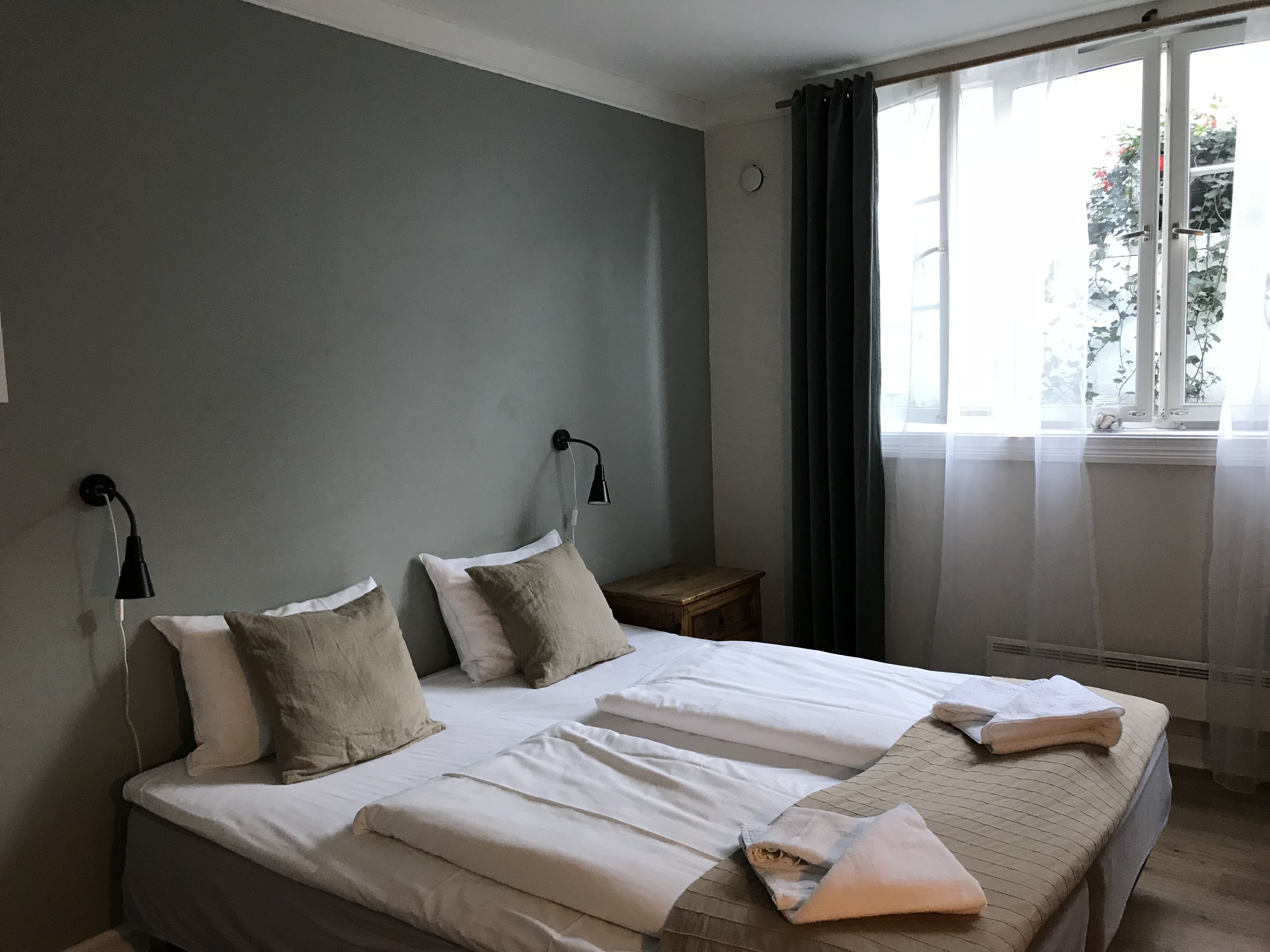 A neatly made bed with pillows, a bedside table, and a lamp.