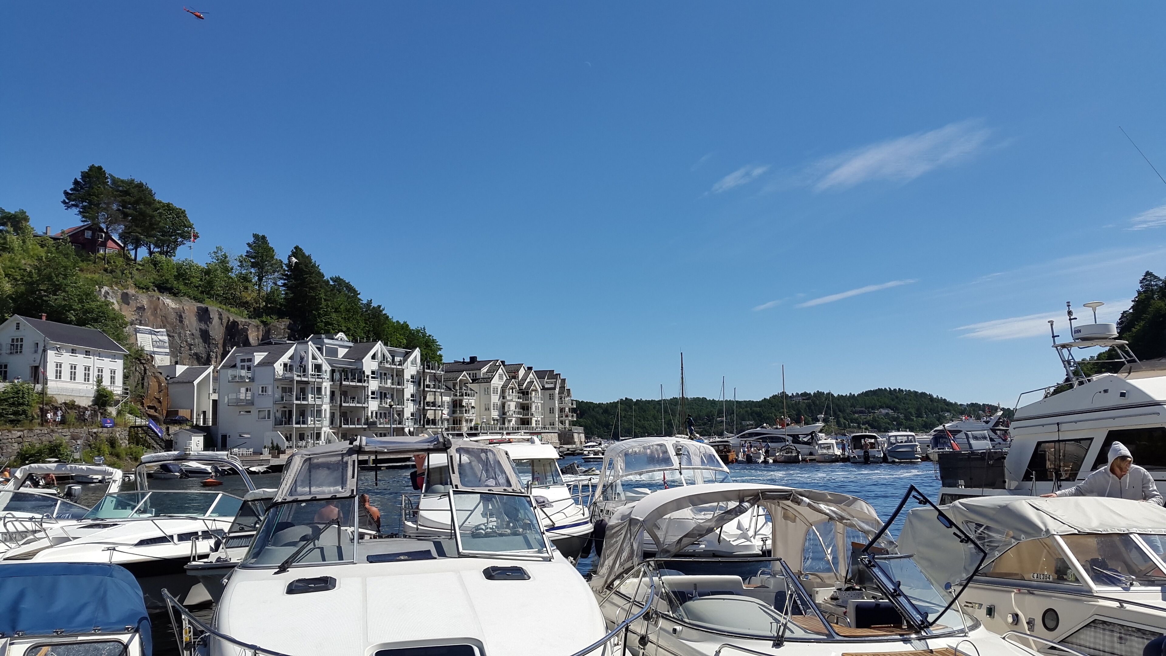 Un port de plaisance où sont amarrés de nombreux bateaux, un immeuble doté de balcons et un ciel d’un bleu limpide.