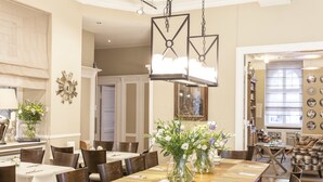 A spacious dining area with a long wooden table, multiple chairs, and decorative vases. - Hotel Elba am Kurfürstendamm - Design Chambers (Berlin)
