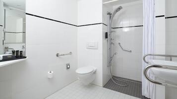 Un baño moderno con inodoro, lavamanos, ducha y un perchero para toallas.