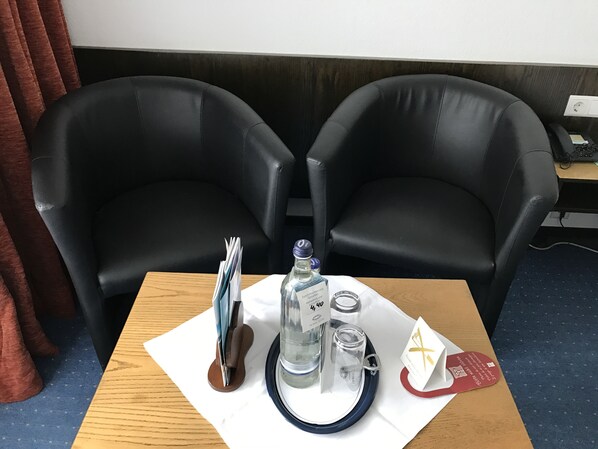 A room with two black leather chairs, a wooden table with a bottle, glasses, and a menu. - Hotel Rheinlust (Boppard)
