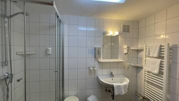 Une salle de bain moderne avec une douche à parois de verre, un lavabo et une serviette accrochée au mur, ainsi qu’un radiateur blanc.