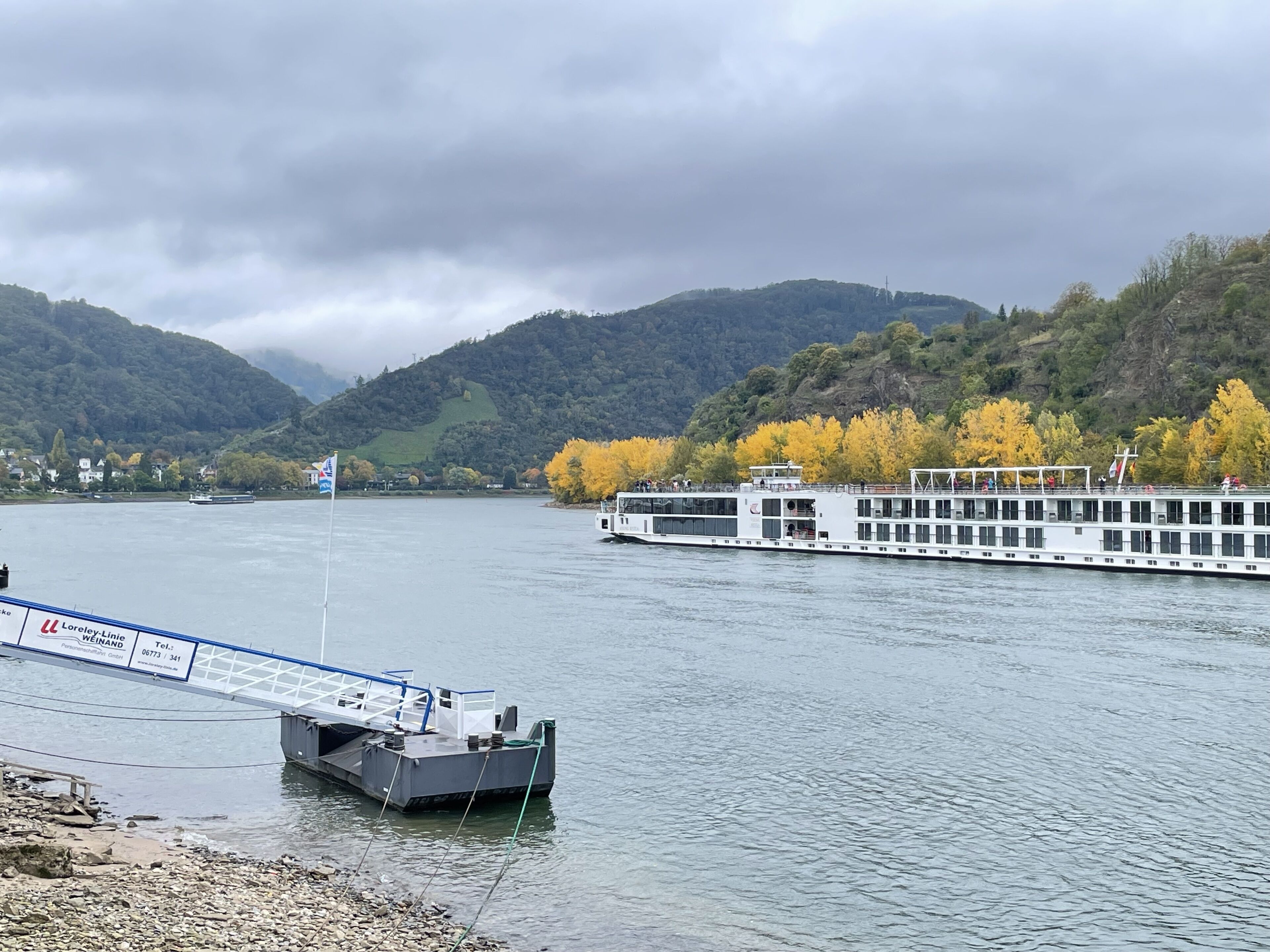 A river with a large white boat docked at a pier.