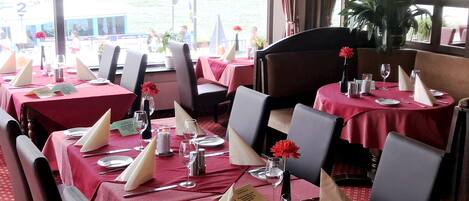 Un restaurante con mesas dispuestas para comer, con manteles rojos y servilletas blancas.