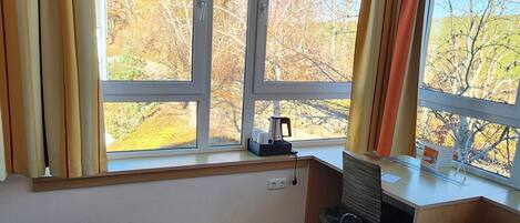 A hotel room with two beds, a desk, a chair, and a TV.