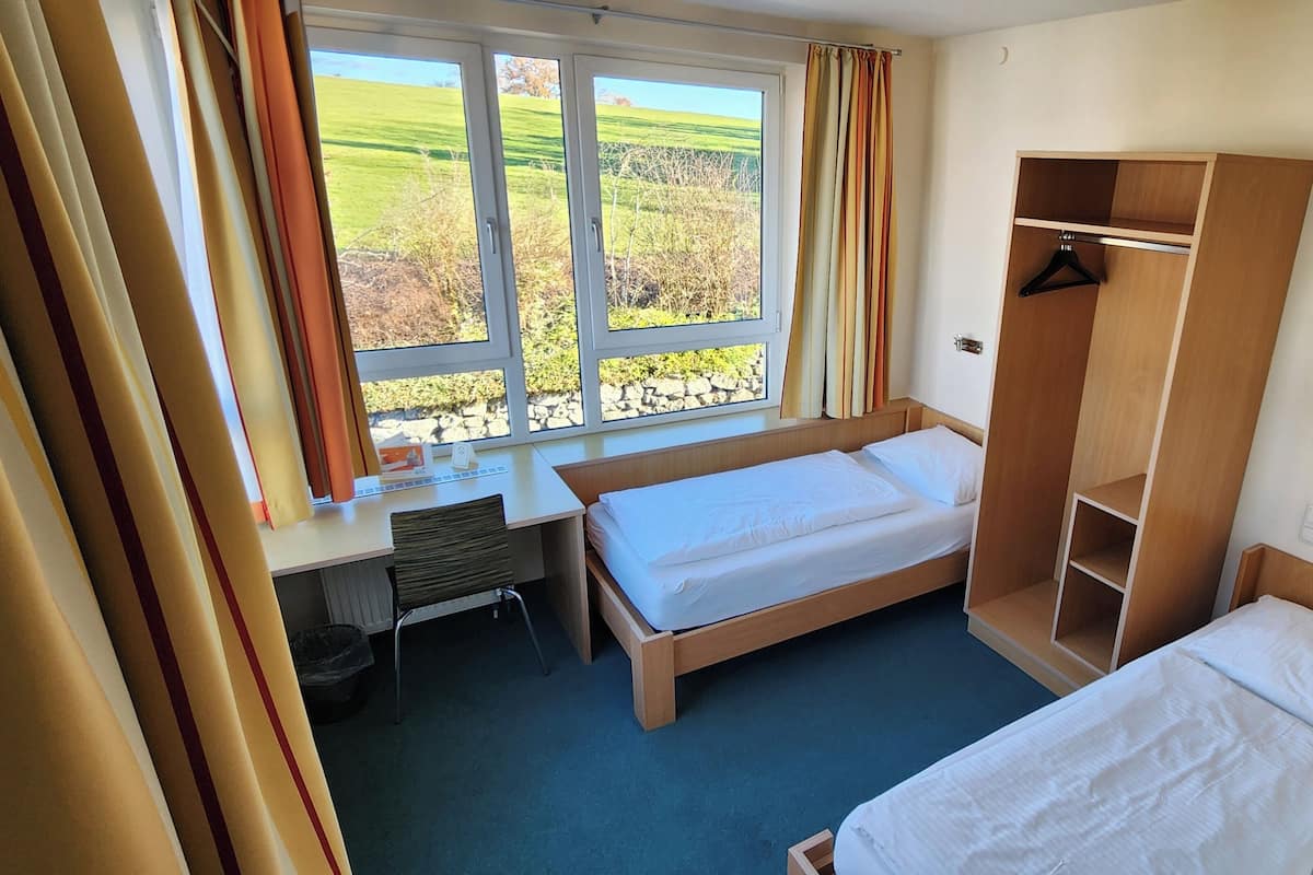 A hotel room with a bed, a desk, and a wardrobe.
