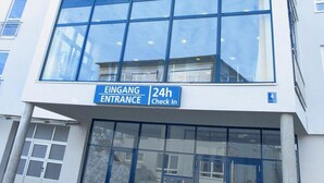 Un edificio moderno con un cartel que dice 'Smart Motel' y servicio de recepción las 24 horas.