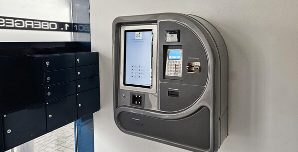 Un quiosco autoservicio con pantalla táctil, teclado y ranura para tarjetas, probablemente para acceso a la habitación o pago.