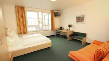 Una habitación de hotel con dos camas, un escritorio, una silla, un televisor y una ventana con cortinas.