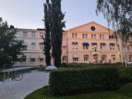 Un edificio histórico con fachada simétrica, ventanas grandes y un reloj central.