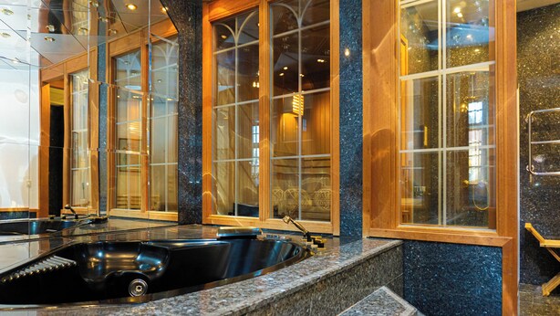 A modern bathroom with a large black bathtub, granite countertops, and wooden accents. - Furunäset Hotell och Konferens (Pitea)