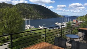 A terrace with a view of a lake, boats, and a forested hill. - Oscarsborg Castle Hotel & Resort (Frogn)