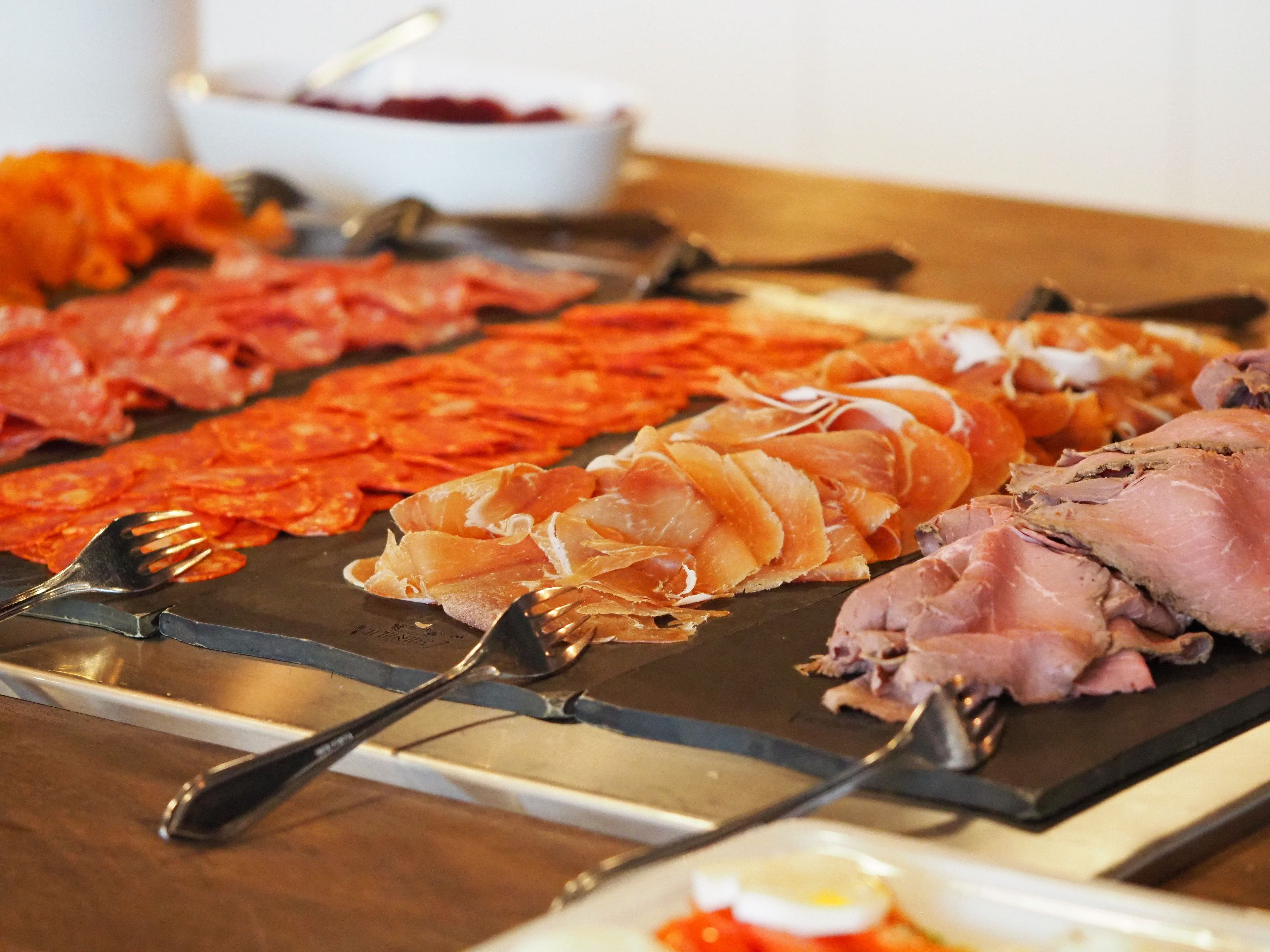 A variety of meats on a grill with forks.