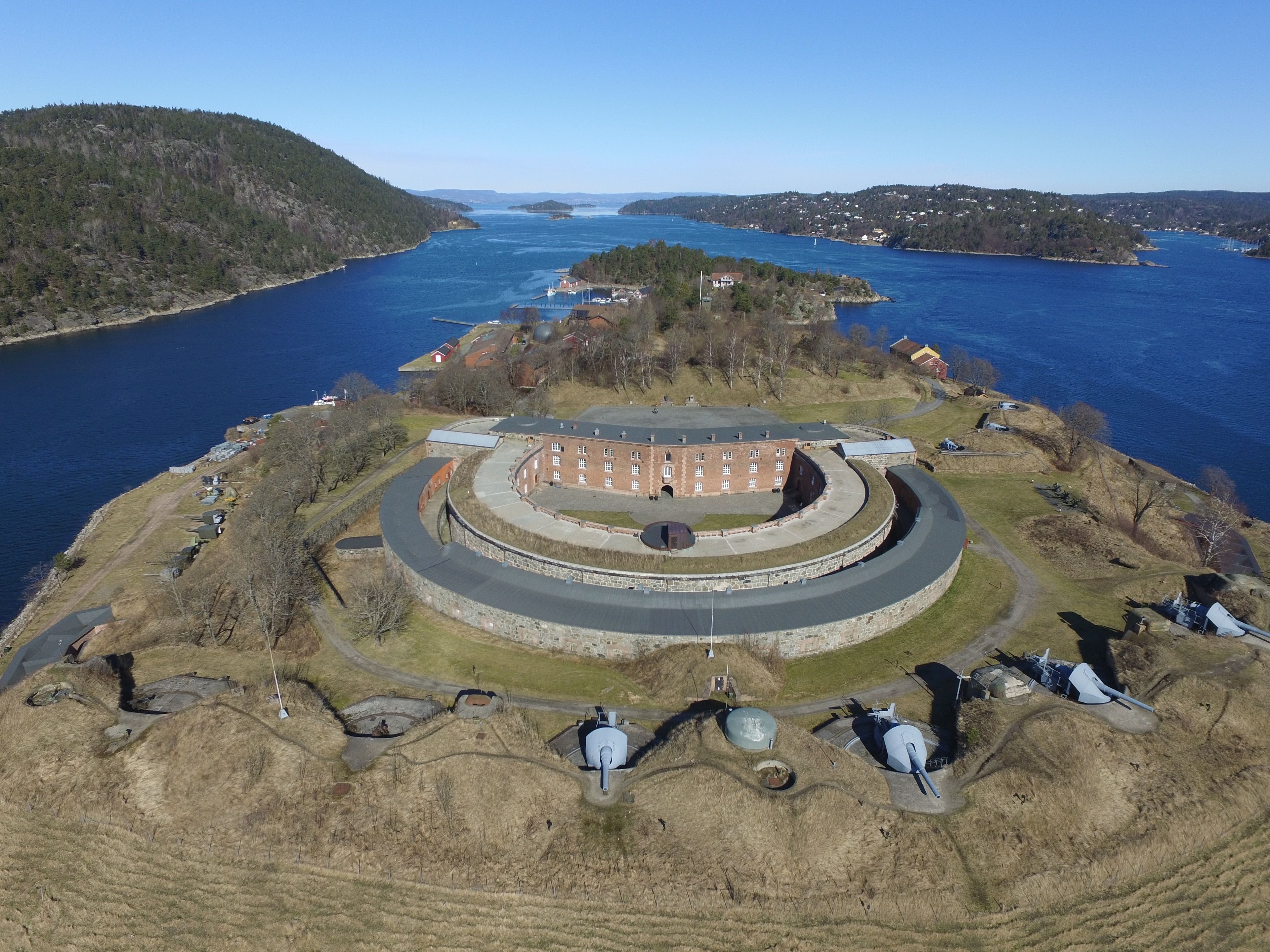 A coastal fort with a circular layout, a large central building, and several smaller structures.